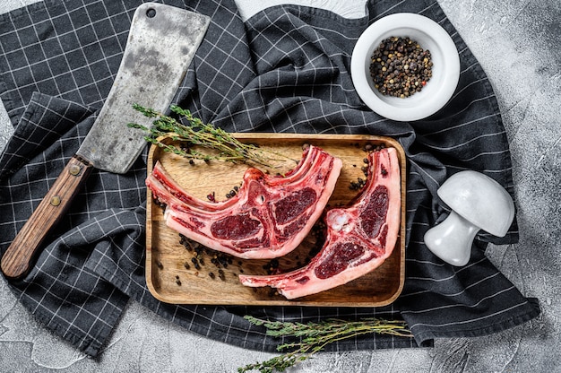 Carne di agnello cruda sulle costole con rosmarino e spezie. sfondo grigio. vista dall'alto