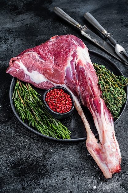 Carne di coscia di montone di agnello crudo con osso alle erbe vista dall'alto.