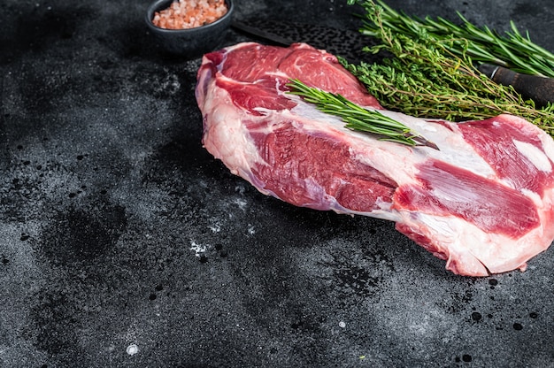 Raw lamb mutton shoulder meat in a baking dish with thyme and garlic