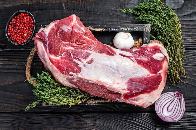 Raw lamb mutton shoulder meat in a baking dish with thyme and garlic