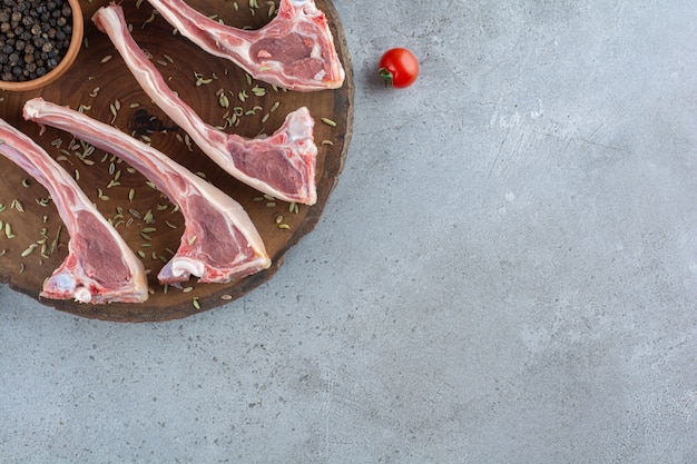 Raw lamb ribs placed on a stone table.