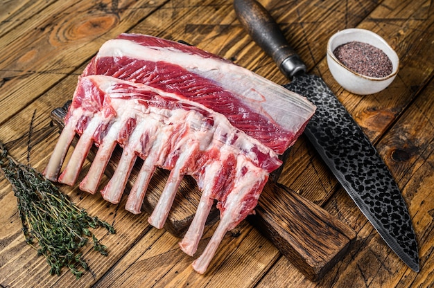 Raw lamb ribs rack on a cutting board with knife