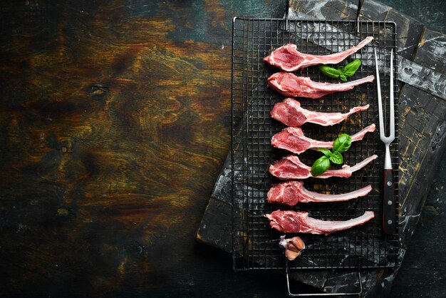 Costolette di agnello crude e condimenti alla griglia per preparare il barbecue vista dall'alto della carne