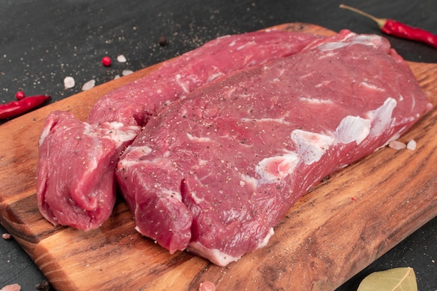 Raw lamb tenderloin fillet or mutton sirloin meat. Fresh sheep fillet, loin filet with spices on a wooden cutting board closeup