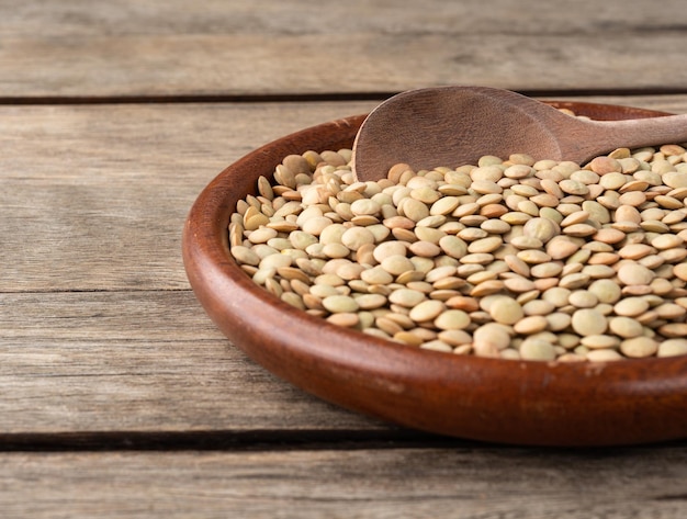 Raw lentils in a plate over wooden table with short depth of field