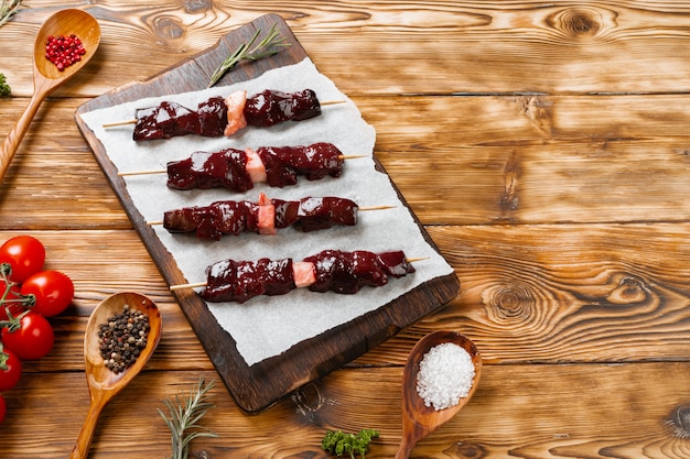 Raw liver kebab on skewers on wooden board