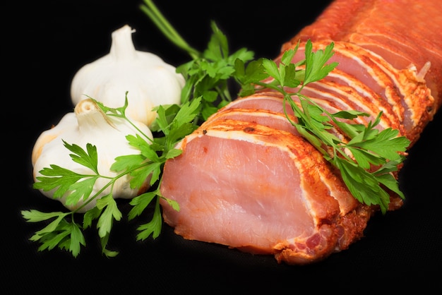 Raw loin, pork meat with garlic and parsley on black isolated background
