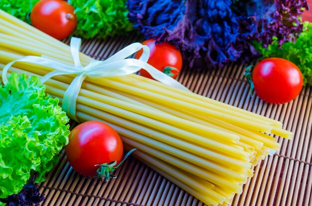 Raw and long pasta and vegetables on the table