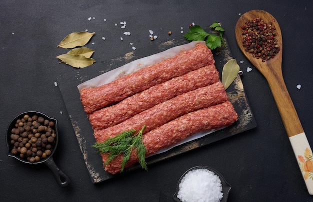 Raw lula kebab sausages on a board and spices top view