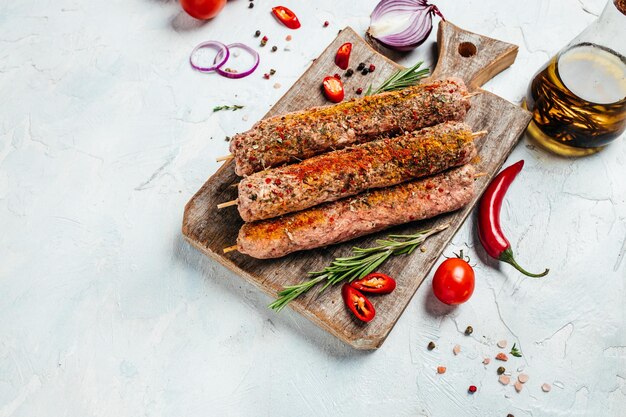 Raw Lula kebab on skewers with spices on a cutting board light background Lula kebab traditional Caucasian dish Long banner format top view