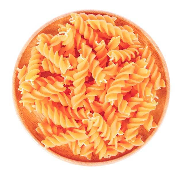 Raw macaroni on wooden plate top view