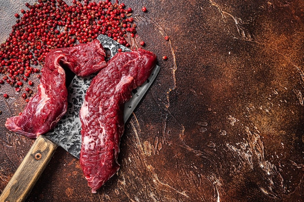 Raw Machete steak and flap steak flank cut on butcher meat cleaver Dark background Top view Copy space