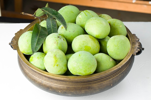 Raw mango or Green mango arranged in a traditional brass vessel