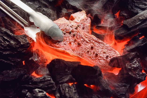 生の霜降り牛肉ステーキ、石炭と煙