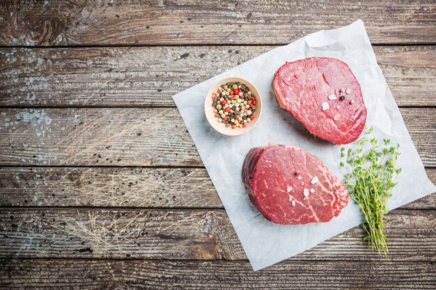 Raw marbled meat steak Filet Mignon with seasonings over stone background, top view.