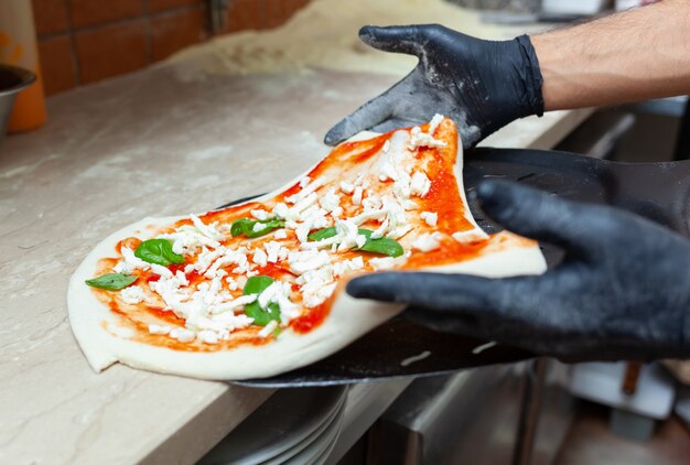 Raw margherita pizza on baking shovel.