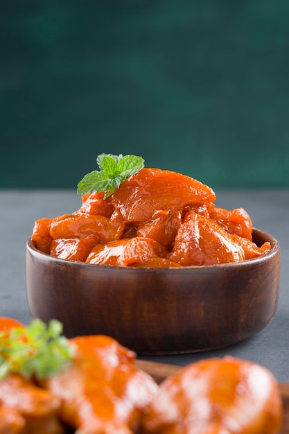 Raw marinated chicken cubes and legs or drum sticks arranged in a wooden tableware garnished with fresh coriander and mint leaf which is placed on grey textured background,selective focus.