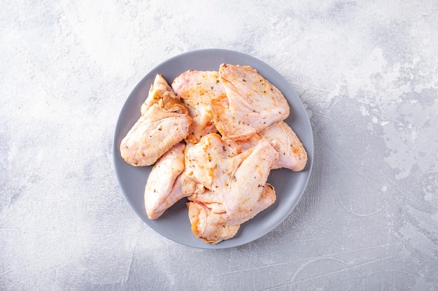 Raw marinated chicken wings on a plate ready to cook Top view Text space