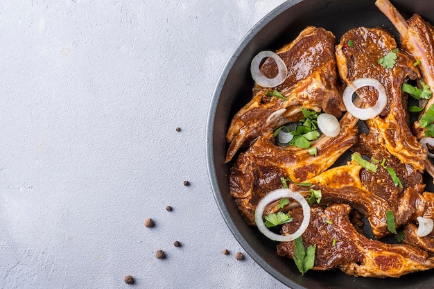 Raw marinated lamb meat on a frying pan Space fpr text Top view