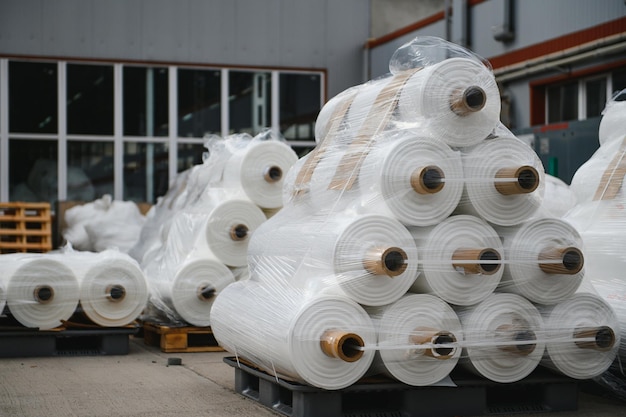 原材料倉庫。工業用バッグを作るための織糸で作られた完成したプロピレンホースの多くの大きなコイル。包装用ポリプロピレンロール。