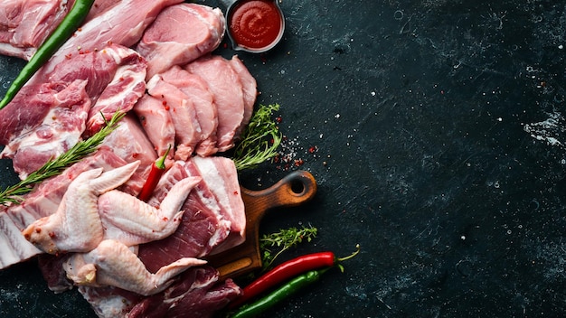 Raw meat background Meat on a black stone background with spices and herbs Top view Rustic style