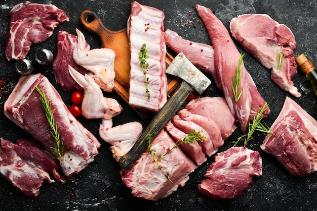 Raw meat background Meat on a black stone background with spices and herbs Top view Rustic style