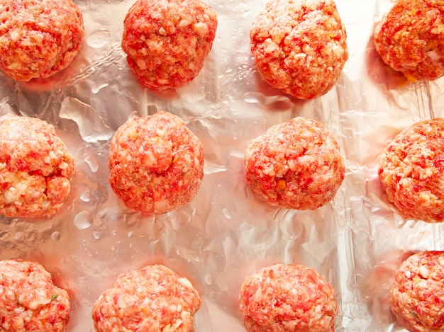 Raw meat balls on foil. Top view.