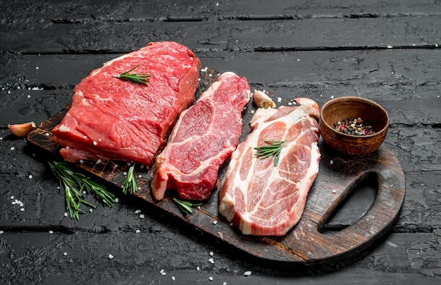 Сырое мясо Стейки из говядины и свинины со специями на разделочной доске
