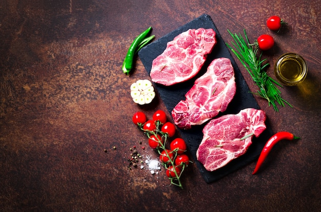 Carne cruda, bistecca di manzo su un tagliere di pietra con rosmarino, spezie