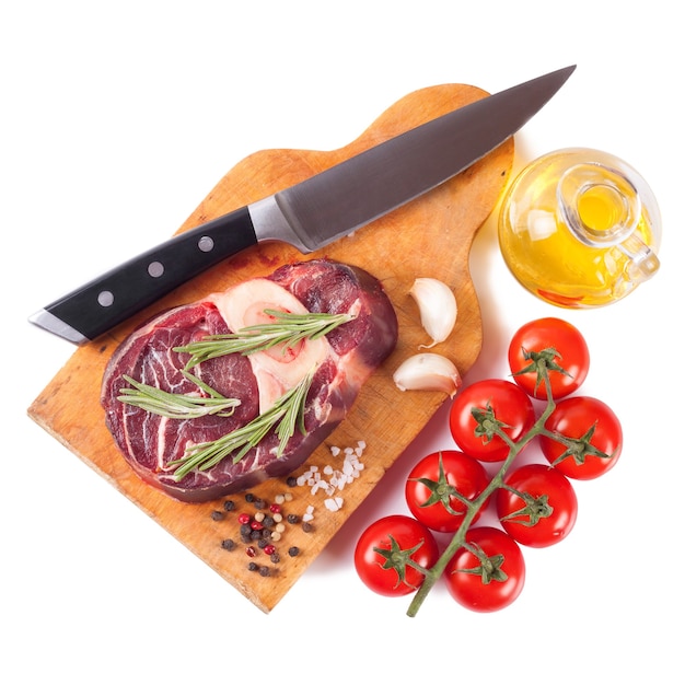 Raw meat beef steak with bone and knife, spices, rosemary and cooking ingredients