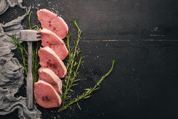 Raw meat Beef steak with rosemary and spices on a black wooden background Top view Free space for text