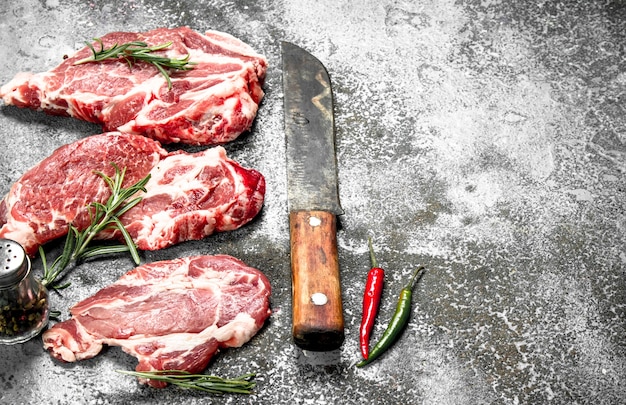 Raw meat of beef with rosemary and hot peppers. On rustic background.