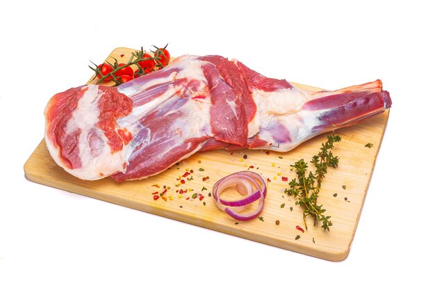 A raw meat on a cutting board with a knife and a slice of red onion.