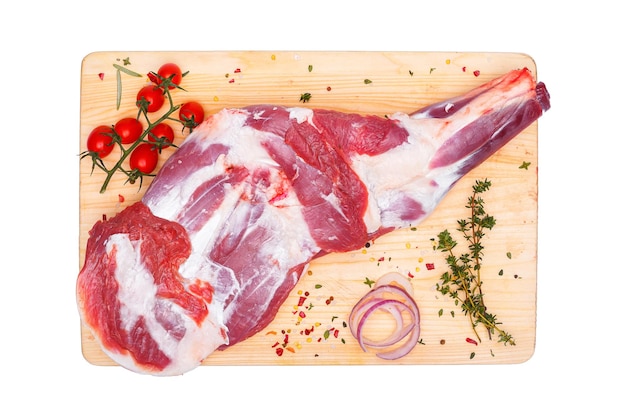 A raw meat on a cutting board with red onions and red peppers on it.