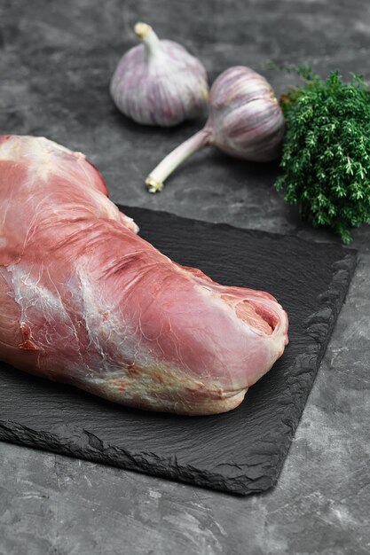 Raw meat on a cutting board with spices on a stone background.