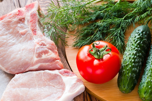 Сырое мясо и свежие овощи на разделочной доске