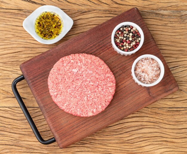 Raw meat hamburger over wooden board with seasonings