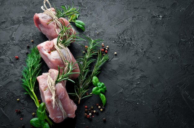 Raw meat medallions with rosemary and spices On a black stone background Top view Free copy space