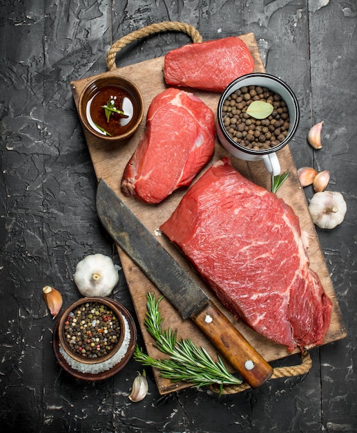 Raw meat Pieces of beef with spices and herbs on a wooden Board