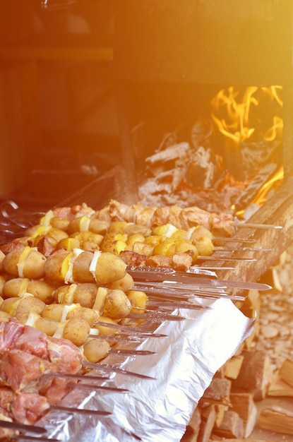 Raw meat and potatoes are planted on metal skewers