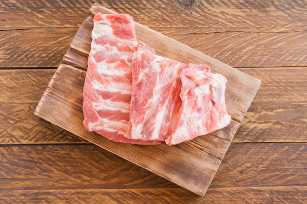 生肉。木製の背景に肉と後ろから生の豚カルビ。上面図。