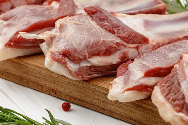 Raw meat ribs on wooden board on white background