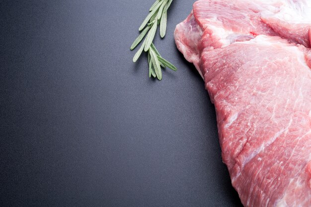 Photo raw meat and rosemary on dark background