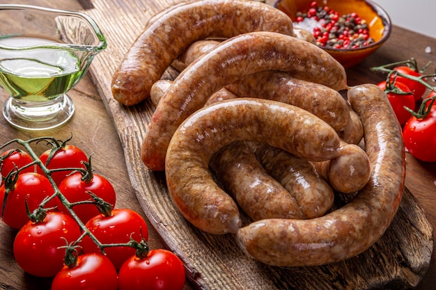 Raw meat sausages from beef and minced pork on wooden cutting board and products for cooking it close up.