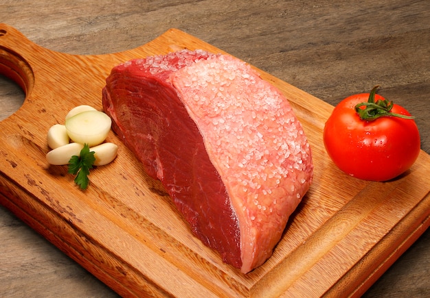 Выбор сырого мяса на деревянной разделочной доске.