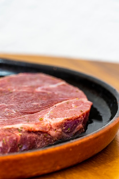 Сырое мясо подается в черной глиняной посуде на деревянном столе в мексике