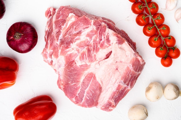 Raw meat set with ingredients and herbs on white stone table background top view flat lay