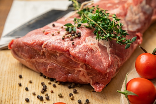 Pezzi di carne cruda a fette di manzo con spezie ed erbe aromatiche su una tavola di legno