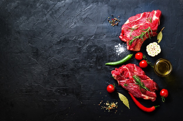 Raw meat steak on a stone cutting board with herbs