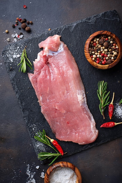 Raw meat steak with spices on rusty background